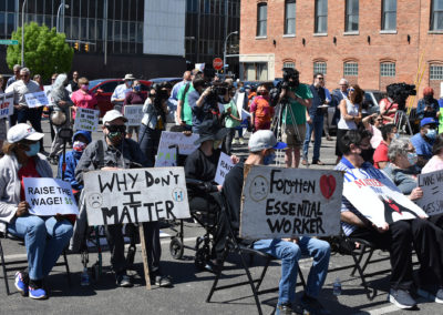 A group of people sit with signs during a press conference