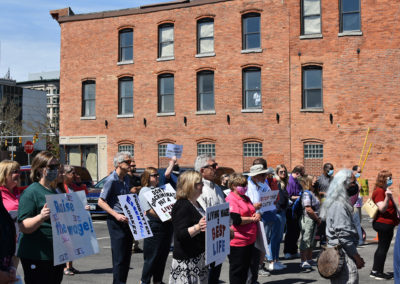 A group of people stand holding signs advocating for pay increases for DSPs