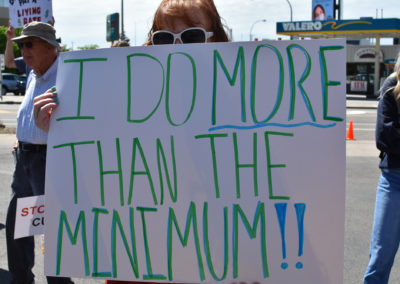 A woman holds a sign advocating for more pay for DSPs