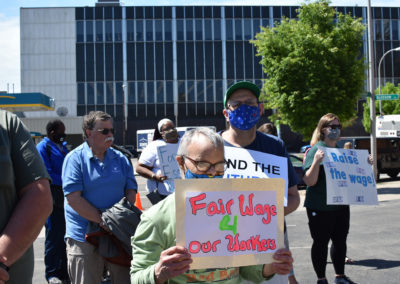 A man holds a sign asking for fair wages for DSPs