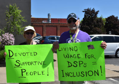 Photo of a woman and a man holding signs