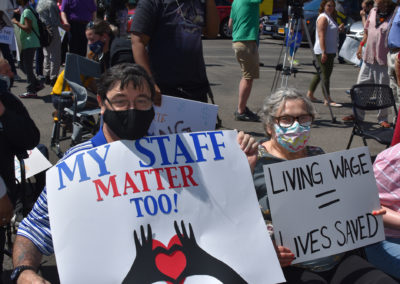 A man and a women hold signs advocating for pay increases for DSPs