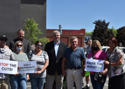 A group of people hold signs advocating for higher pay for DSPs